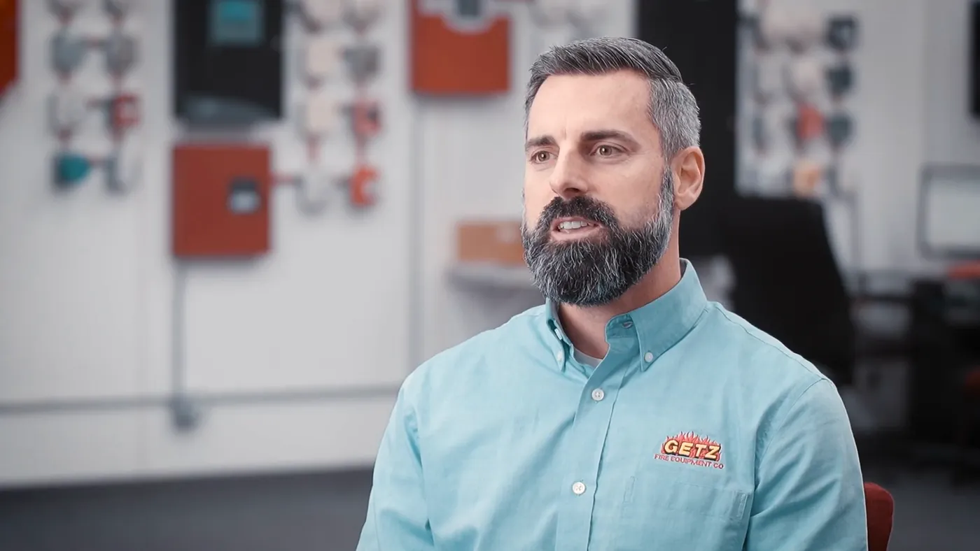 Jason Getz, President of Getz Fire Equipment, in front of a wall of fire alarm panels
